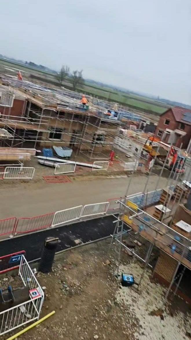 View down from a scaffold over a new housing site, with houses at different stages of the build